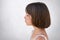 Sideways portrait of adorable freckled girl looking into distance while having dreamy expression over white concrete wall