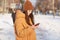 Sideways shot of female youngster dressed in stylish hat and loose jacket, holds mobile phone, surfes social networks and watches