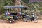 Siem Reap, Cambodia - 01.05.2018; Tuk-Tuk driver waits in the shade for clients and looks at his mobile phone