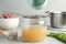 Sieving delicious bone broth into glass jar on light grey table