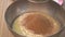 Sifting cocoa powder into bowl on table on wooden background