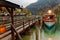 Sightseeing boat parking by a wooden pier at beautiful lakeside in a misty foggy morning on Lake Konigssee