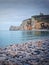 Sightseeing view to Etretat coastline with the famous Notre-Dame de la Garde chapel on the Amont cliff. Pebble beach washed by