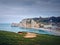 Sightseeing view to Etretat coastline with the famous Notre-Dame de la Garde chapel on the Amont cliff. Seashore washed by