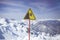 Sign on background of mountains. Sign warning of danger of falling. Triangle on stick. Symbol on yellow background. Carefully