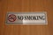 Sign board for no smoking is placed on the wooden surface.