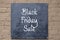 Sign board painted black screwed onto painted concrete block wall -Black Friday Sale written in chalk
