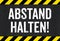 Sign with caution stripes - Keep distance in german - Abstand halten