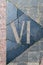Sign on the cobblestones in the form of a Roman numeral six. Street paving. Cobblestone pavement