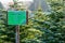 Sign with German lettering `Christmas trees sale` in front of frost covered evergreen fir trees on a Christmas tree farm