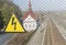 Sign of high voltage on the background of the railway.