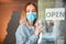 Sign Open welcome on shop entrance door as new normal.Young woman portrait in medical protective mask gloves hangs on front door