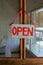 Sign painted in red, with the word \'open\' hangs from nail on old wood and screen door of shop