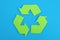 Sign of recycling made of green paper on a blue background, the concept of protection, preservation of the environment