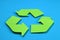 Sign of recycling made of green paper on a blue background, the concept of protection, preservation of the environment