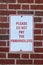 Sign that says please do not pay the panhandlers posted on brick wall - close-up
