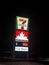 A sign of a Seven Eleven, Petro Canada with the price of gas and a Car Wash sign at night. A