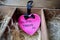 Sign in the shape of a pink heart with the inscription do not disturb in a wooden box with straw