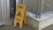 Sign showing warning icon of wet floor. Yellow signboard standing on concrete surface. Exhibition hall caution notice