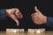 Sign of thumbs up and thumbs down to show the like and unlike feeling. Hands and wood blocks isolated on black background.