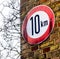 Sign on a wall with yellow bricks indicating the maximum applicable speed of 10 kilometres per hour