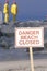 A sign warning, dangerï¿½beach closed with cleanup crews in the background