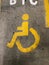 Sign of a yellow person and wheelchair on the floor in a parkinglot