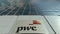 Signage board with PricewaterhouseCoopers PwC logo. Modern office building facade. Editorial 3D rendering