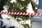 Signal striped tape near trees in the snow. Park hazard warning. Attention - snow melting. Warning signs for people