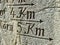 Signpost carved in stone with an arrow and the distances of 4 and 5 kilometers