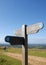 A signpost and a couple walking with a dog on the South Downs Way near Brighton in Sussex, England, UK