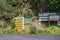 Signpost with multiple destinations and distances near welcome and advertising sign at Port Fitzroy