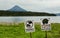 Signs warn of the danger of meeting tourists with bears on background of Kurile Lake and Ilyinsky volcano.