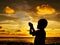 Sihlouette of praying kid during sunset
