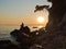Sihouette of a girl sitting on a rock at sunset, Kastani Mamma Mia beach, island of Skopelos