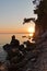 Sihouette of a young couple sitting on a rock at sunset, Kastani Mamma Mia beach, island of Skopelos