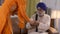 Sikh family early morning scenario: Daughter-in-law serving tea to father-in-law.  Old sikh man reading Gutka