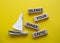 Silence your inner critic symbol. Wooden blocks with words Silence your inner critic. Beautiful yellow background with boat.