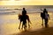 Silhouetes of tourists riding horses on ocean beach at sunset, Bali, Indonesia