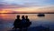 Silhouette of 3 senior women enjoying a colorful sunset on a bench at a beautiful lake.