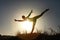 Silhouette of acrobatic teen gymnast balancing with the sun behind