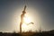Silhouette of acrobatic teen gymnast balancing with the sun behind