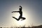 Silhouette of acrobatic teen gymnast jumping with the sun behind