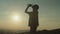 Silhouette of active sporty fit asian woman drinking water on mountain top at sunset