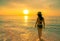 Silhouette adult woman walking at tropical sea with beautiful sunset sky at paradise beach. Happy girl wear bikini and straw hat