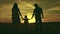 silhouette affectionate parents with child sunset. happy african family sunset park. mother father hold kid hands