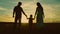 silhouette affectionate parents with child sunset. happy african family sunset park. mother father hold kid hands