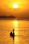 Silhouette of African fisherman in canoe at sunset