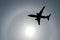 Silhouette of an airplane in the sky sun and halo in the clouds.