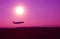 Silhouette of airplane taking off up to purple sky with bright sun